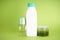 White bottle of shampoo, body scrub and deodorant on a green background