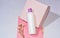 White bottle for shampoo and cosmetics with place to write and logos on pink background with plaster and flower.