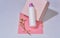 White bottle for shampoo and cosmetics with place to write and logos on pink background with plaster and flower.