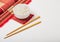 White bowl with boiled organic basmati jasmine rice with wooden chopsticks and sweet soy sauce on bamboo placemat with red linen