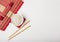 White bowl with boiled organic basmati jasmine rice with wooden chopsticks and sweet soy sauce on bamboo placemat with red linen