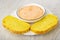 White bowl with creamy fish oil, slices of cornbread in plate on table