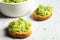 A white bowl and crostini with guacamole