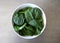 White Bowl of Fresh Baby Spinach Leaves against a Gray Background