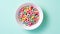 White bowl with fruit cereal rings on a light blue background, top view banner