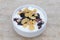 White bowl with muesli, berry, flakes, yogurt and honey, close up