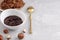 White bowl with natural hazelnut oil, golden spoon, healthy cookies, hazelnuts on a light background. Vegetarian traditional