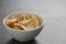 White bowl with organic potato chips sprinkled with fresh ground black pepper on concrete background with copy space