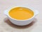 White bowl of papaya soup on wooden table