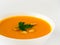 White bowl of pumpkin soup, garnished with parsley
