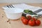 White bowl and a sprig of cherry tomatoes on a wooden table