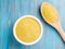 White bowl and wooden spoon with raw couscous on blue wooden ba