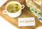 White bowl with yellow chicken soup with green dill with a note `secret ingredient`