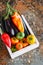 White box with vegetables on a rusty background. Aubergines, bell pepper, tomatoes. Overhead view and copy space.