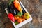 White box with vegetables on a rusty background. Aubergines, bell pepper, tonatoes.