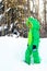 White boy in a green Dragon snowsuit standing on a snowbank