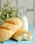 White bread loafs and glass of milk. Freshly bakery food. Light rustic breakfast and bouquet of field daisies on light