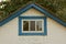 White brick attic of a rural house with a small blue window