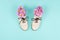 White brogue shoes filled with pink daisies and wildflowers on pastel blue background