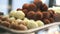 White,brown tasty sweets with sprinkling lie on the counter metal plate close-up