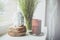 White buddha head figurine on wooden stand with big brown candle a windowsill, green floral plant background. Home