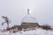 White Buddhist stupa and ritual trees with colorful ribbons on a cloudy winter day at the top of the sacred island of Ogoy