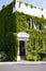 White building with portico overgrown with green curling ivy