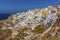 The white buildings of the village of Oia, Santorini tumble down the cliff towards Amoudi Bay