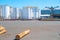 White bulk storage tanks across sealed yard with few logs on ground