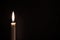 White burning candle on a black background. Mourning, burning candle