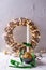 White burning candle, shiny glass cones, rustic wreath with  bright fairy ligts