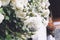 White bushy braided roses in garden on background of stone old house closeup on a sunny summer day, buds of delicate flowers