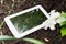 White Business Tablet On Soil With Some Flowers