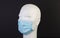 White bust with blue hygienic mask on black background