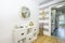 White cabinet in a house entrance hall with a wooden access door with gold security hinges, white joinery, access to a kitchen and