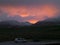 White camper van on the country road along the snow capped mountain range under beautiful sunset sky