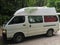A white camper van in the forests of New Zealand, stamped with t