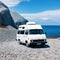 A white camper van is parked on rocky ground in front of in the style of