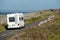White camper van on a small asphalt road in Burren area, Ireland. Cloudy sky. Traveling in motor home concept. Warm sunny day