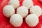 White candies with coconut, nuts and cream on a red background