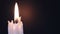 White candle on a black background. Lit flame then blown out