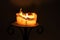 White candle with flame and melting wax on an iron candlestick a