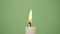 A white candle on a green or olive background. A candle is burning on a green background. 4K resolution video