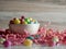 White candy bowl of jelly beans for Easter on a bed of pink paper shreds with a wooden background