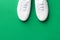 White canvas laced unisex shoes on green background. Classic casual sport footwear youth teenager urban fashion active lifestyle