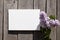 White canvas mockup with lilac flower on wooden wall