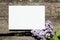 White canvas mockup with lilac flower on wooden wall