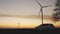 White car on the background of wind turbines at sunset