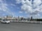 White car crossing a low-cost metropolitan highway long bridge and tenement buildings behind under blue cloudy sky