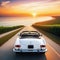 A white car drives off into the sunset along the road to the ocean